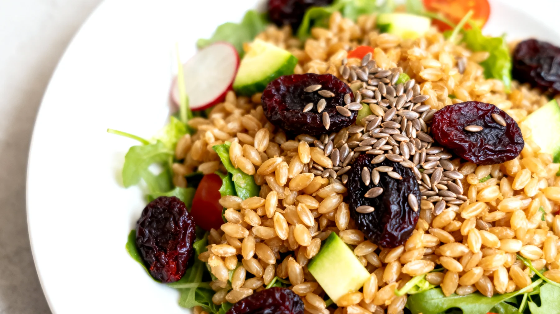 Insalata di farro con prugne secche, semi di lino e verdure crude"